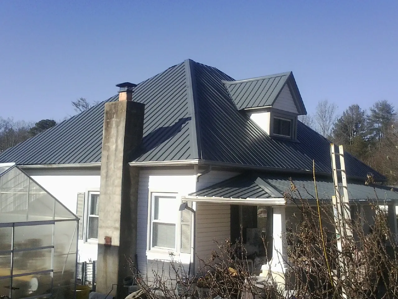 Dark blue standing seam metal roof on a white farmhouse with dormer — Slate & Tile Roof Repair by Roofing Brothers in Taylorstown