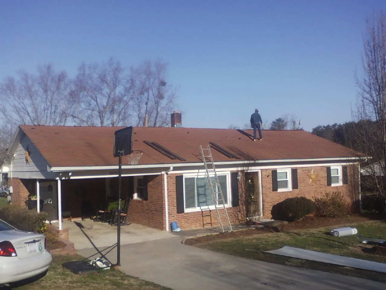 Roofer stripping a shingle roof on a brick ranch before metal panels in Taylorstown