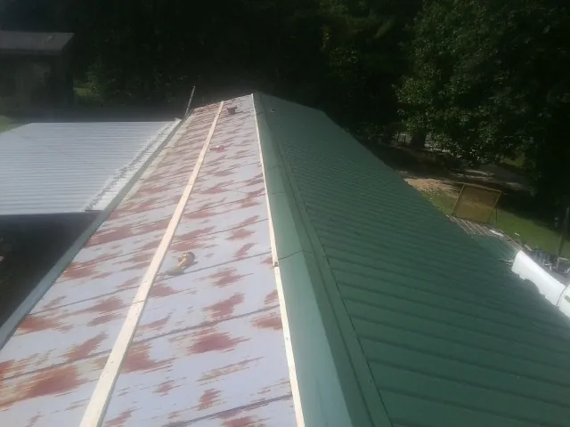 Old rusted panels beside newly installed green metal roofing — Wind Damage Roof Repair by Roofing Brothers in Taylorstown