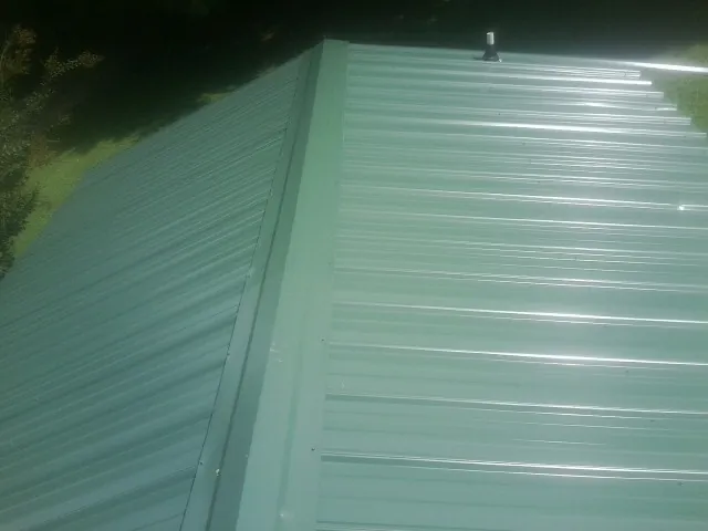 New green metal panels meeting at the ridge of a roof — Flat Roof Repair work by our crew in Taylorstown