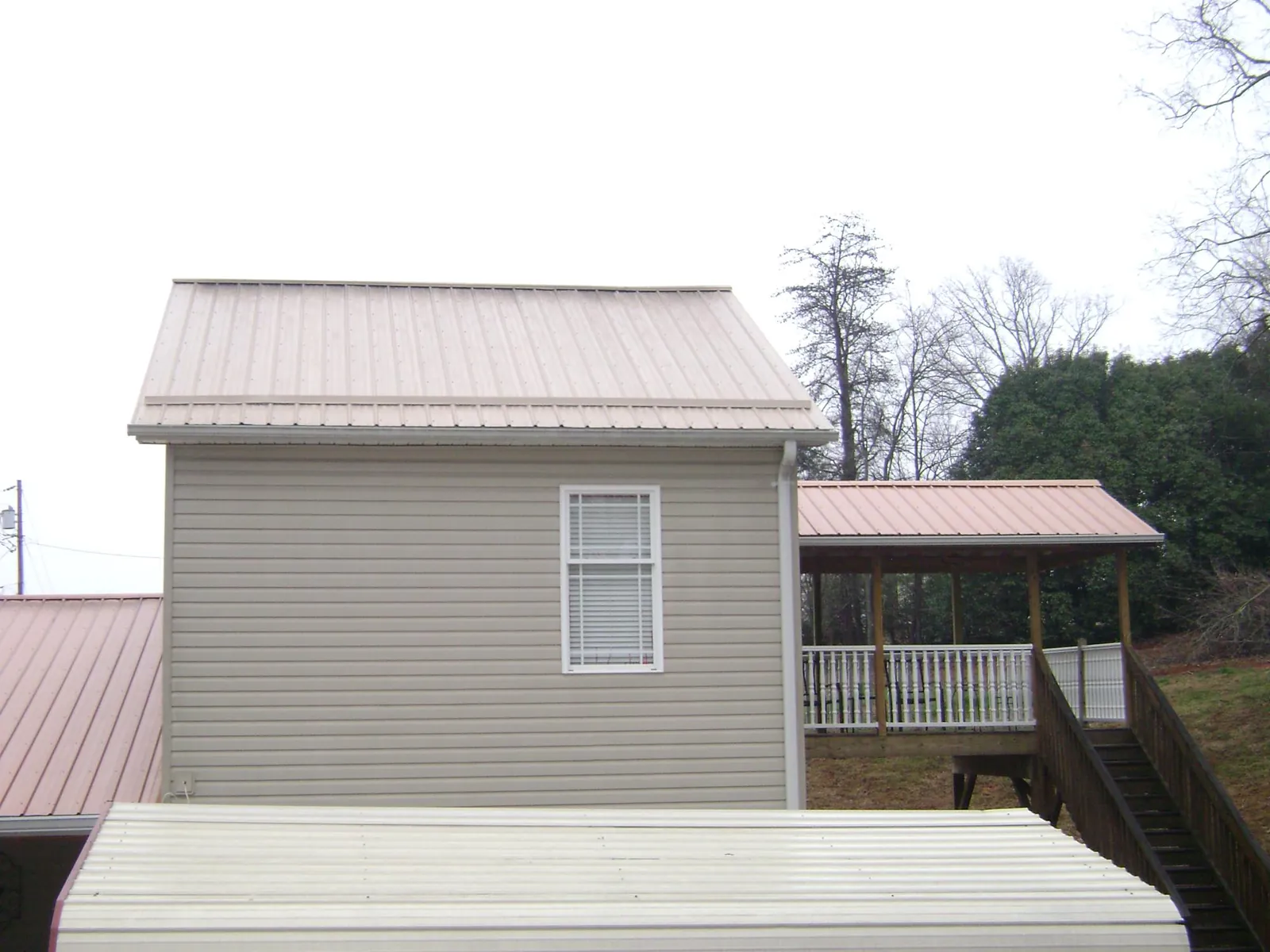 Tan metal roofs on a two story addition and attached porch, from a Roof Replacement job in Taylorstown