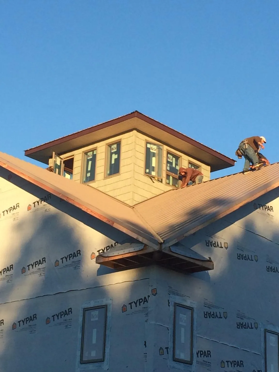 Roofers working around a rooftop cupola on a new metal roof at sunset — Roof Waterproofing in Taylorstown by Roofing Brothers